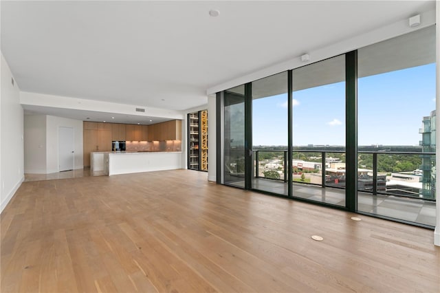 unfurnished living room with floor to ceiling windows and light wood-type flooring