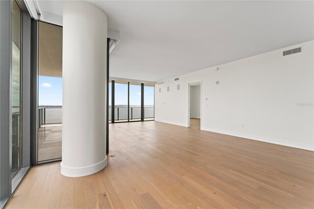 spare room featuring a wall of windows and light hardwood / wood-style flooring