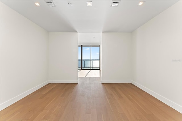 empty room with light hardwood / wood-style floors and a wall of windows