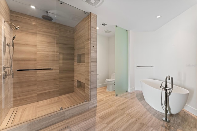 bathroom with toilet, hardwood / wood-style flooring, and shower with separate bathtub