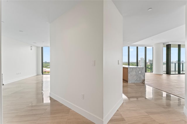 corridor featuring expansive windows and light tile patterned flooring