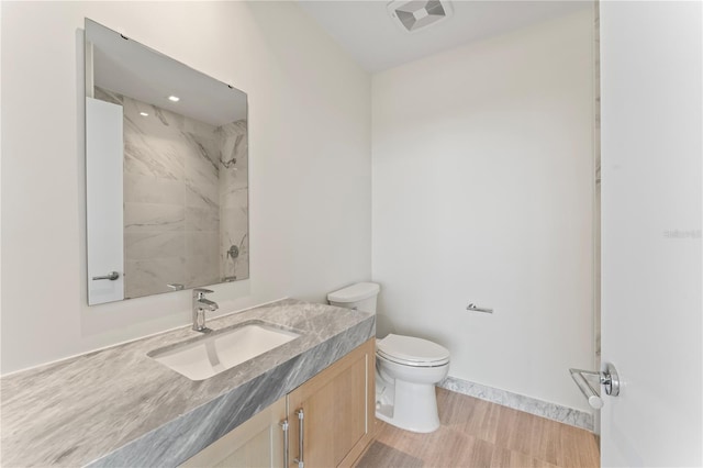 bathroom featuring vanity, toilet, hardwood / wood-style flooring, and tiled shower