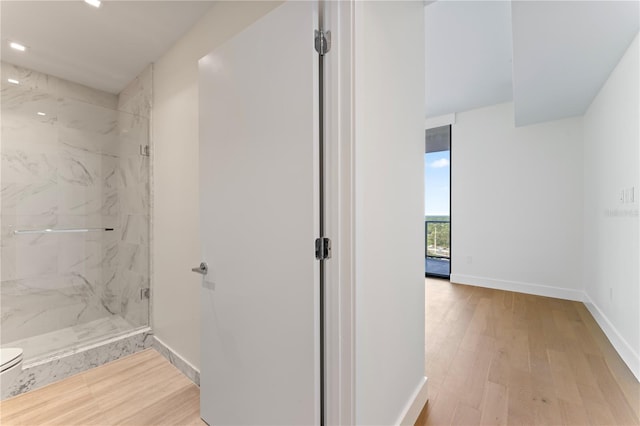 bathroom featuring a shower with door, wood-type flooring, and toilet