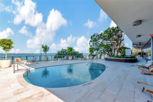 view of pool with a patio and a water view