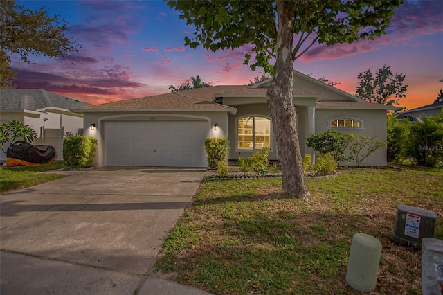 ranch-style house with a garage and a lawn