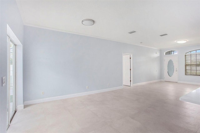 spare room with baseboards, ornamental molding, visible vents, and a healthy amount of sunlight