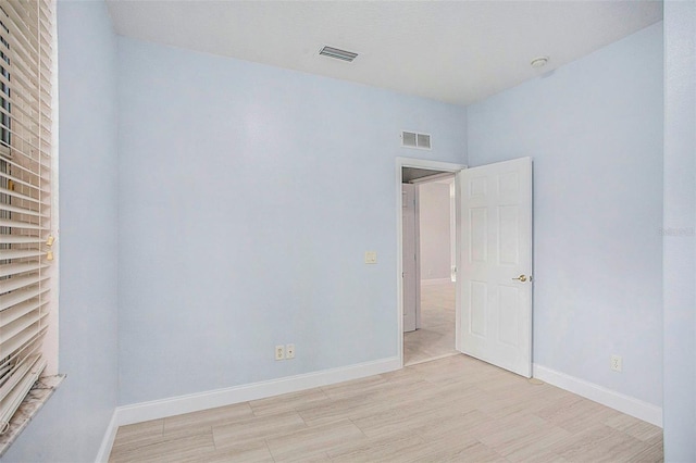 unfurnished room featuring light wood-type flooring, visible vents, and baseboards