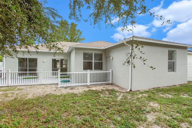 rear view of property with a yard, a patio, fence, and stucco siding