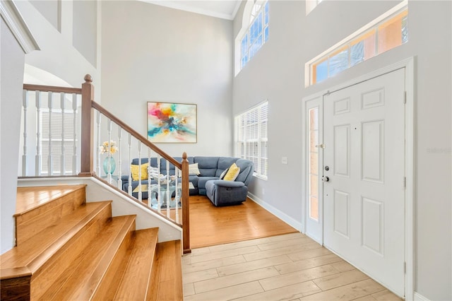 entrance foyer featuring crown molding, a high ceiling, and light hardwood / wood-style flooring