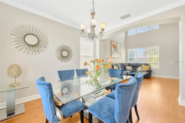 dining room featuring a chandelier, light hardwood / wood-style floors, and crown molding