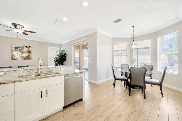 kitchen with light stone counters, dishwasher, hanging light fixtures, and plenty of natural light