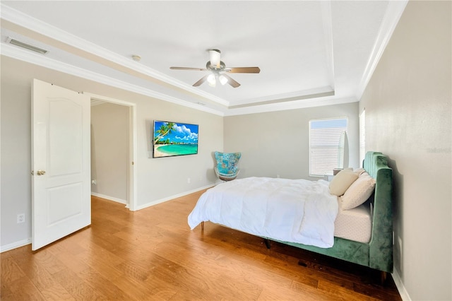 bedroom with hardwood / wood-style flooring, ceiling fan, a raised ceiling, and crown molding