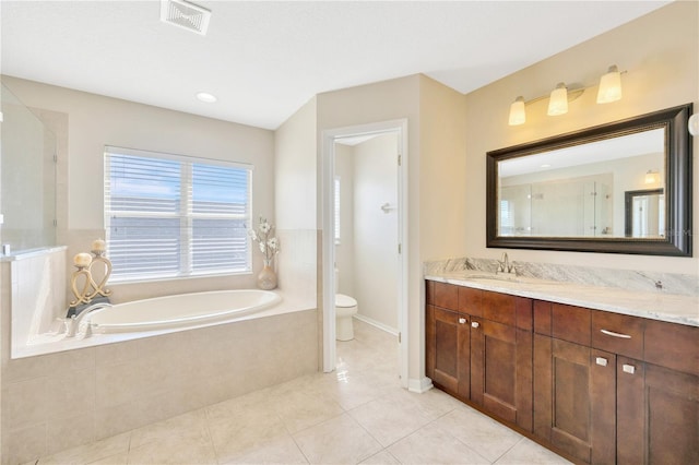 bathroom featuring tile patterned floors, vanity, a relaxing tiled tub, and toilet