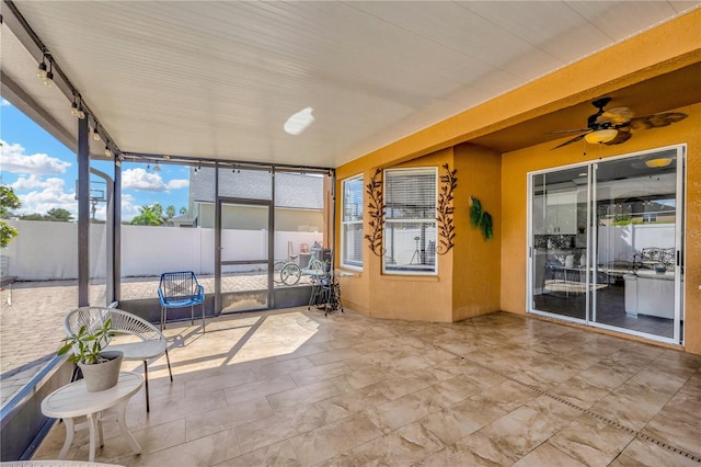 unfurnished sunroom featuring ceiling fan and track lighting