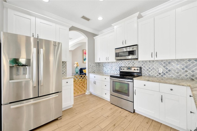 kitchen featuring light stone counters, light hardwood / wood-style flooring, white cabinets, and appliances with stainless steel finishes