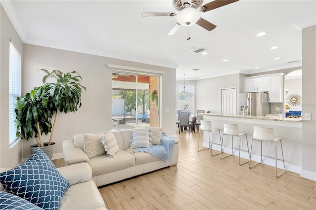 living room featuring ceiling fan, light wood-type flooring, and ornamental molding