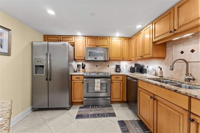 kitchen featuring backsplash, light stone counters, sink, appliances with stainless steel finishes, and light tile patterned flooring