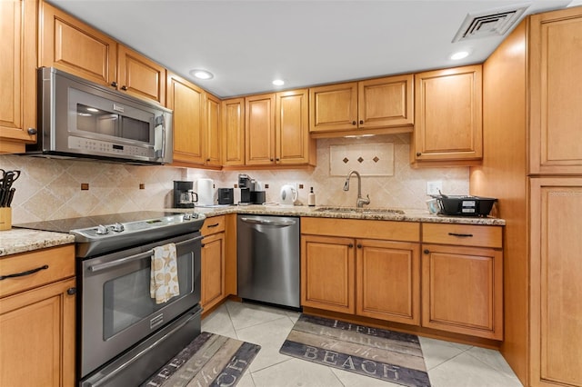 kitchen featuring backsplash, light tile patterned floors, light stone countertops, stainless steel appliances, and sink