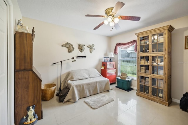 bedroom with ceiling fan, light tile patterned floors, and a textured ceiling