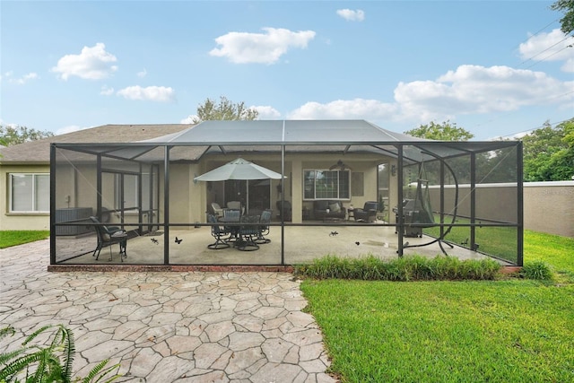 back of house with glass enclosure, a patio area, and a lawn