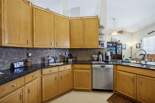 kitchen with dark stone countertops, light tile patterned floors, stainless steel dishwasher, sink, and ceiling fan