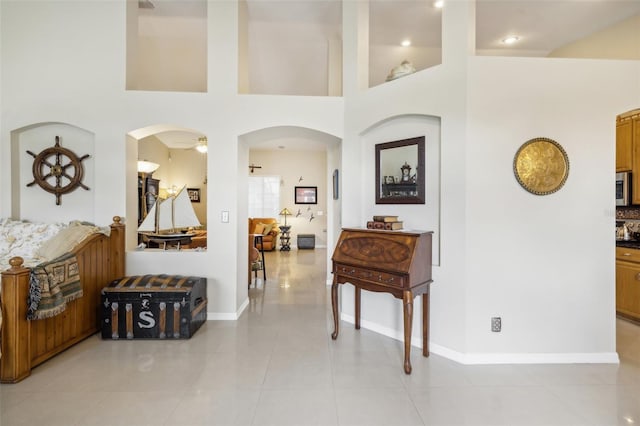 hall with a high ceiling and light tile patterned flooring