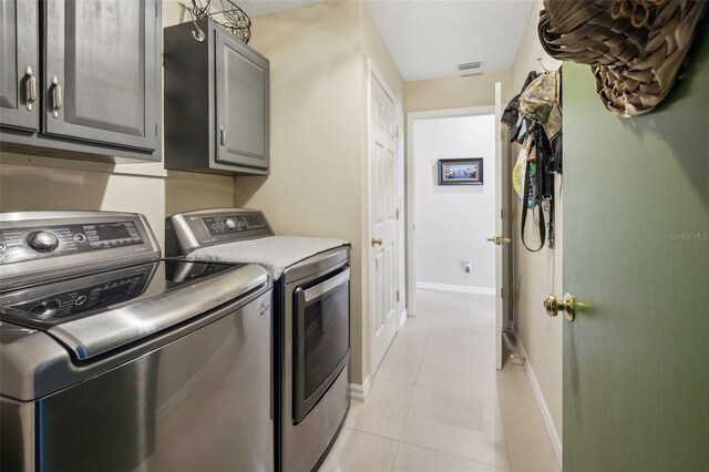 clothes washing area featuring independent washer and dryer, cabinets, and light tile patterned floors