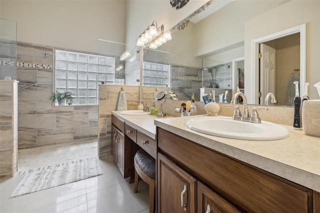 bathroom with tile patterned flooring, vanity, tile walls, and a tile shower