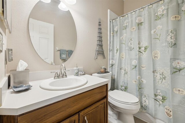 bathroom featuring walk in shower, toilet, and vanity