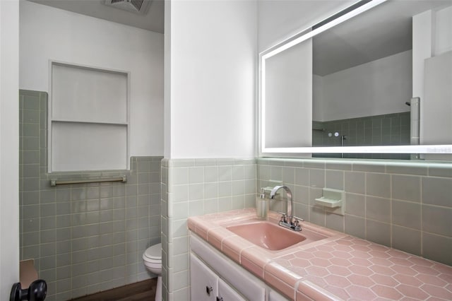 bathroom featuring tile walls, toilet, and vanity