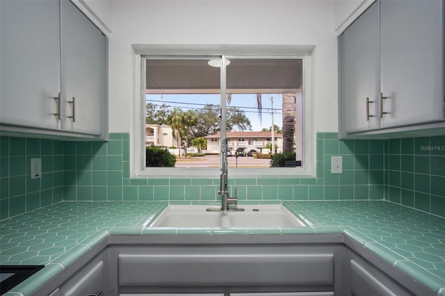 kitchen featuring decorative backsplash, sink, and gray cabinetry