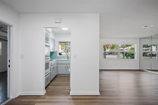 interior space with white cabinetry, wall oven, decorative backsplash, dark hardwood / wood-style floors, and a wealth of natural light