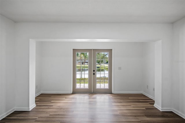 unfurnished room with dark hardwood / wood-style floors, a water view, and french doors