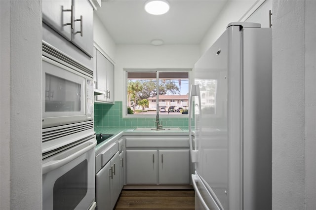 kitchen with white fridge, wall oven, black electric stovetop, decorative backsplash, and white cabinets