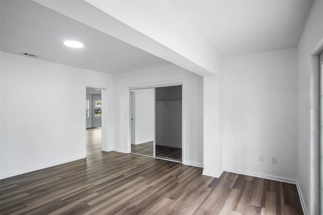 unfurnished bedroom with dark wood-type flooring and a closet