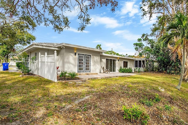 rear view of property featuring a patio area, french doors, and a yard