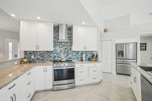 kitchen with white cabinets, light stone counters, stainless steel appliances, wall chimney exhaust hood, and decorative backsplash