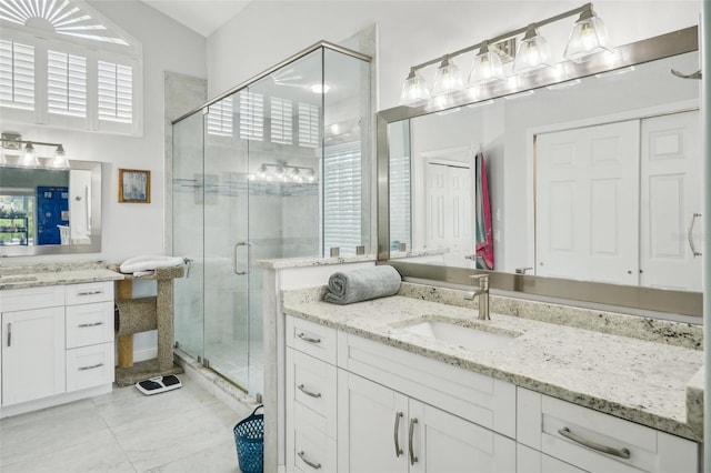 bathroom with a shower with door, vanity, a healthy amount of sunlight, and tile patterned flooring