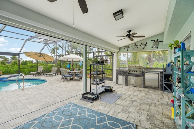 exterior space with a patio area, glass enclosure, grilling area, an outdoor kitchen, and ceiling fan