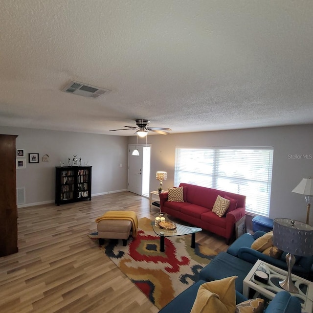 living room with light wood-style floors, visible vents, and a textured ceiling