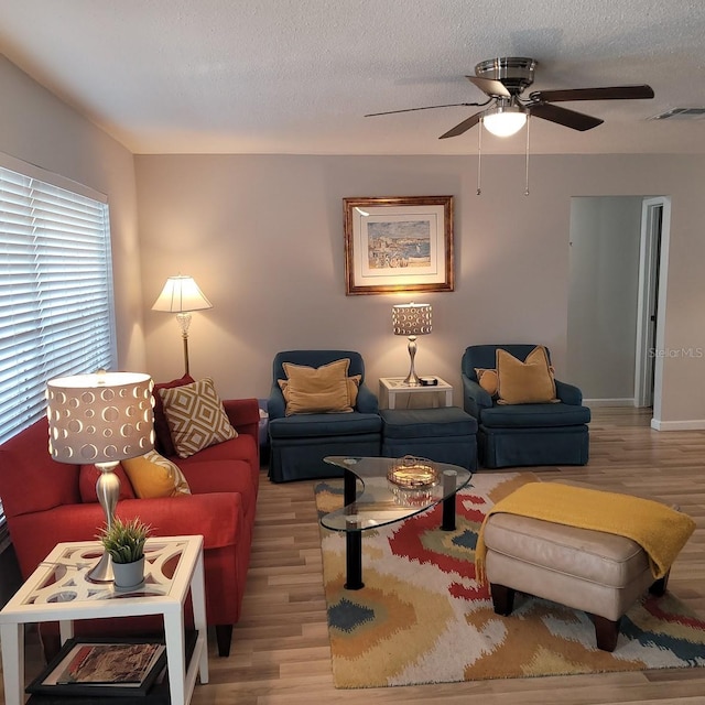 living room featuring visible vents, ceiling fan, a textured ceiling, and wood finished floors