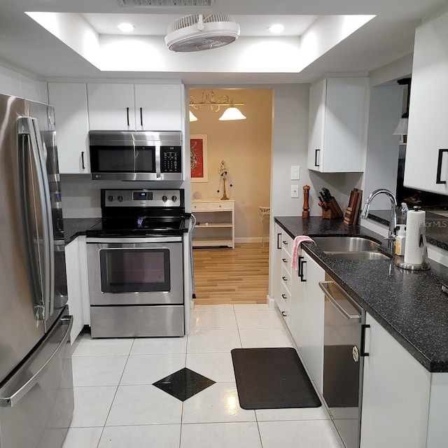 kitchen with light tile patterned floors, stainless steel appliances, a sink, and a raised ceiling