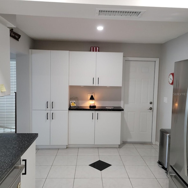 kitchen with freestanding refrigerator, white cabinets, visible vents, and light tile patterned floors