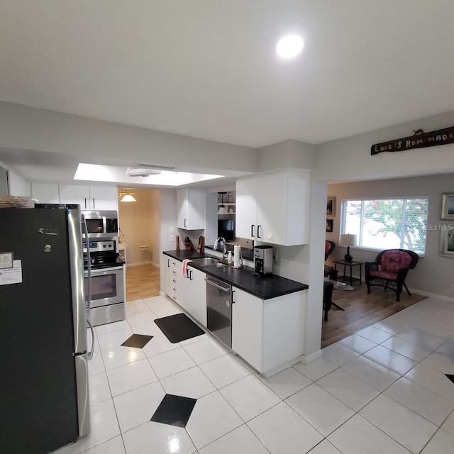 kitchen featuring dark countertops, white cabinetry, appliances with stainless steel finishes, and a sink