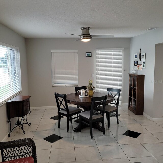 dining area with a textured ceiling, ceiling fan, light tile patterned flooring, and baseboards