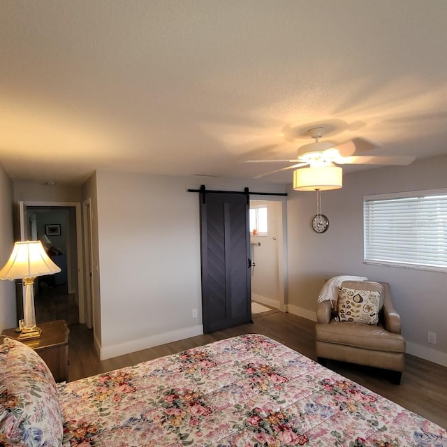 bedroom featuring wood finished floors, ceiling fan, baseboards, and a barn door