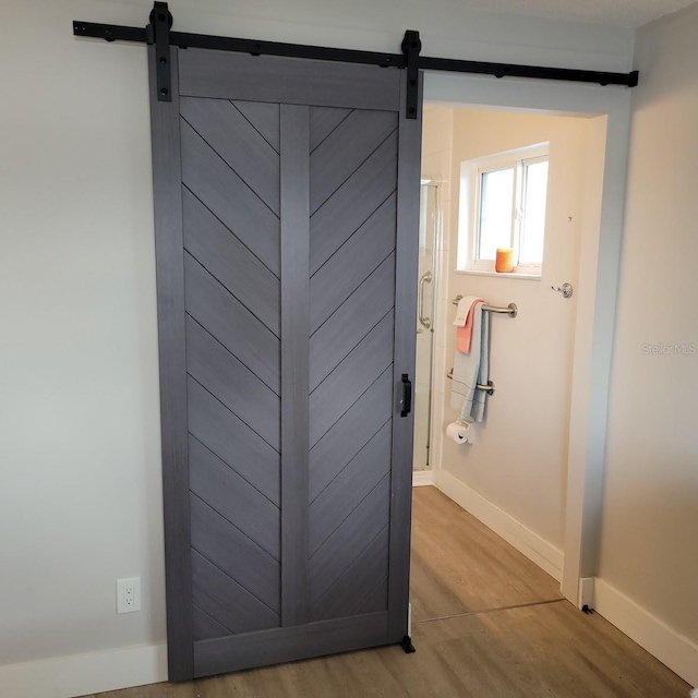 bathroom with a shower stall, baseboards, and wood finished floors