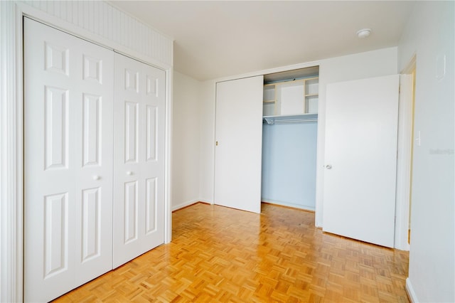 unfurnished bedroom featuring two closets and light parquet flooring