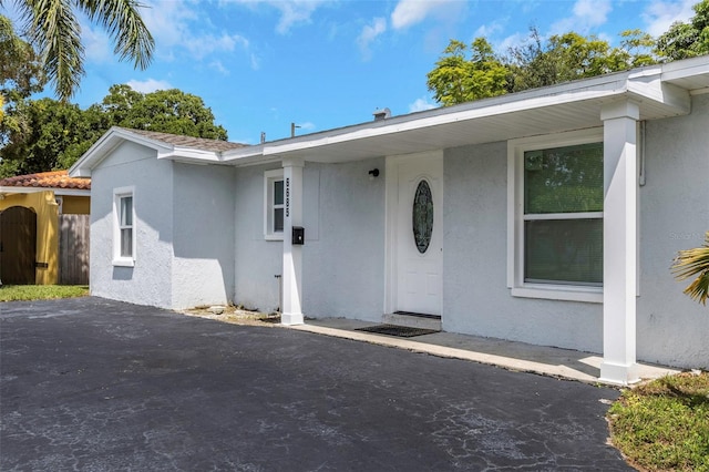 entrance to property featuring fence and stucco siding