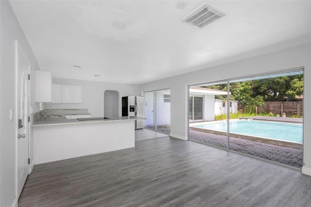 unfurnished living room with wood finished floors, a sink, visible vents, and baseboards